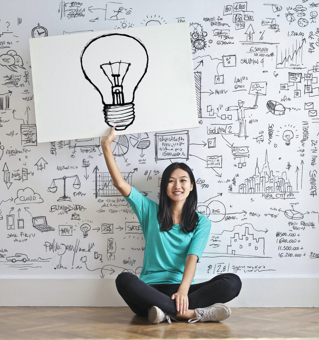 An innovator smiles, pointing to a lightbulb signifying her creativity in the workplace